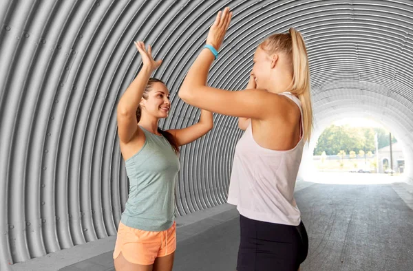 Mulheres felizes com rastreadores de fitness fazendo alta cinco — Fotografia de Stock