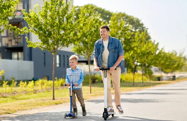 Otec a malý syn jezdi na skútrech ve městě — Stock fotografie