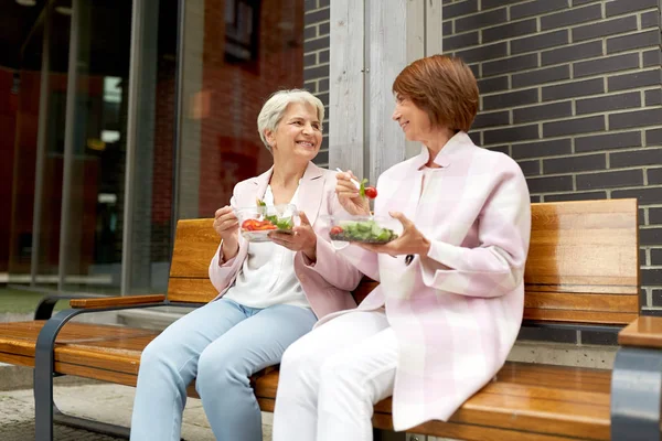 街の通りでテイクアウトの食べ物を食べる高齢者女性 — ストック写真