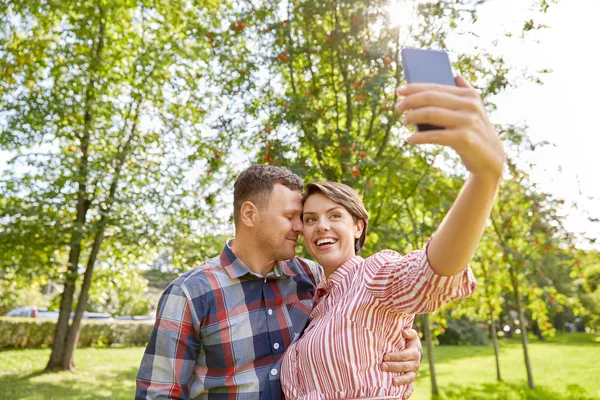 Ευτυχισμένο ζευγάρι στο πάρκο λαμβάνοντας selfie από το smartphone — Φωτογραφία Αρχείου