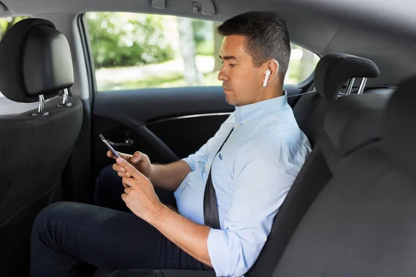 Passager avec écouteurs et téléphone portable en taxi — Photo