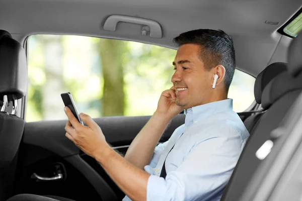 Passagerare med hörlurar och mobiltelefon i taxibil — Stockfoto