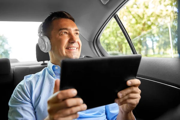Пассажир с наушниками с помощью планшетного ПК в автомобиле — стоковое фото