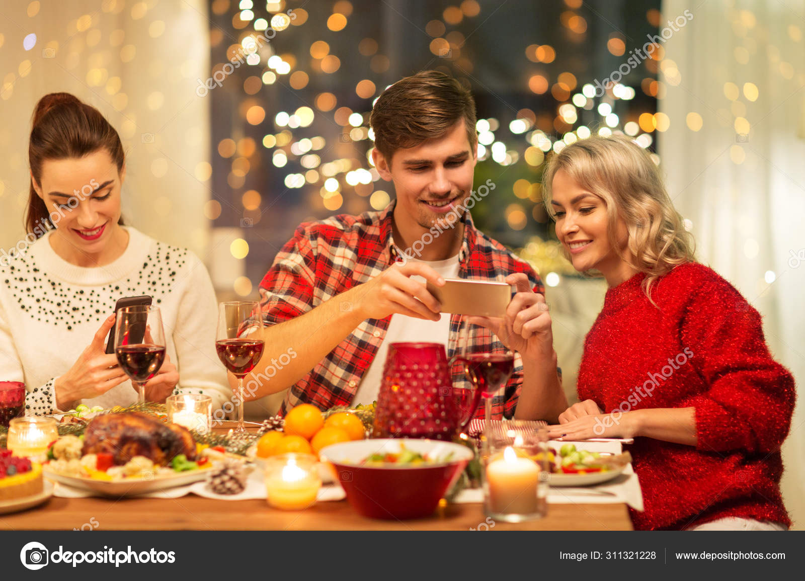 Happy friends having christmas dinner at home Stock Photo by ©Syda