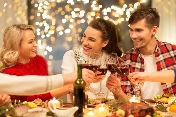 Счастливые друзья пьют красное вино на рождественской вечеринке — стоковое фото