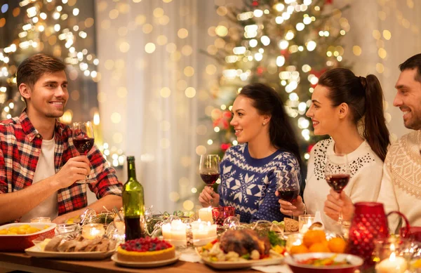 Šťastný přátelé pití červeného vína na vánoční párty — Stock fotografie