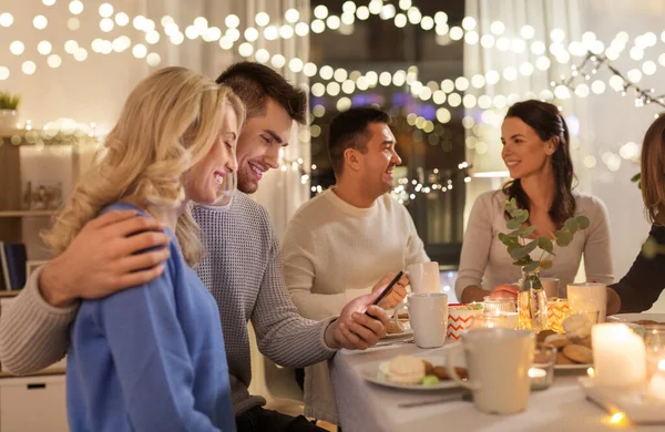 Happy couple with smartphone at family tea party — Stock Photo, Image