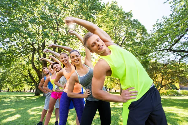 Grupp glada människor motionerar på sommarparken — Stockfoto