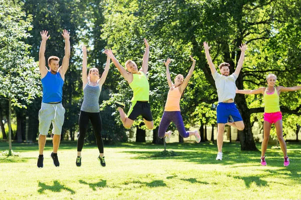Grupo de amigos felices saltando alto en el parque — Foto de Stock