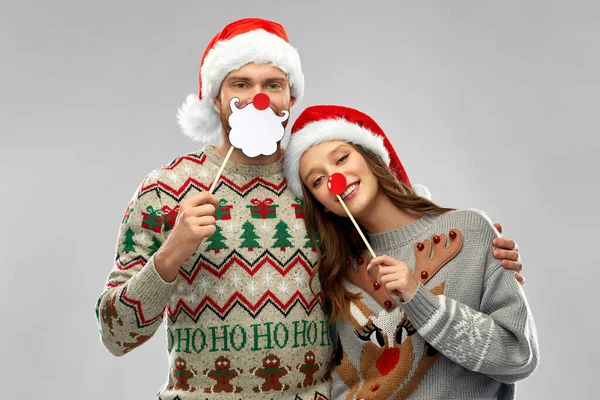 Paar mit Weihnachtsfeier-Requisiten in hässlichen Pullovern — Stockfoto