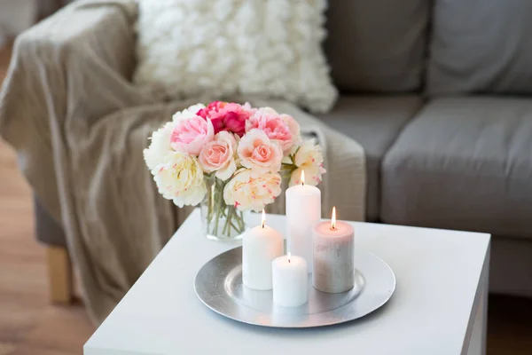 Hořící svíčky na stole a květiny v útulném domě — Stock fotografie
