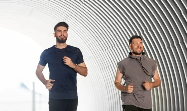 Dos felices jóvenes amigos varones corriendo al aire libre — Foto de Stock