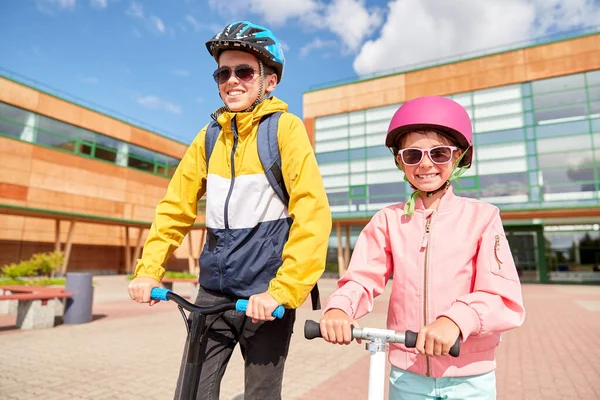 Gelukkige schoolkinderen met rugzakken en scooters — Stockfoto