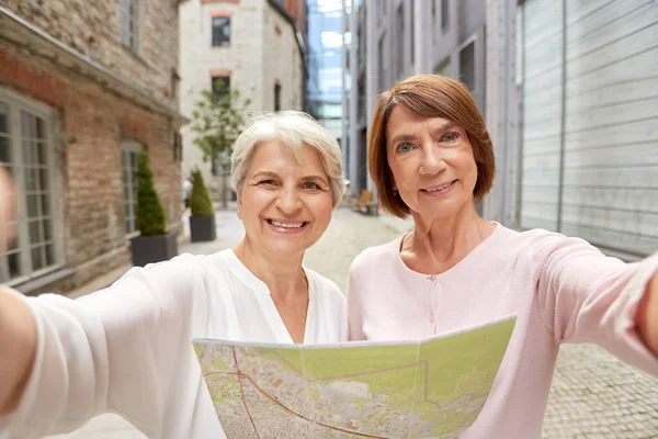 Senior women with city map taking selfie outdoors — Stock Photo, Image