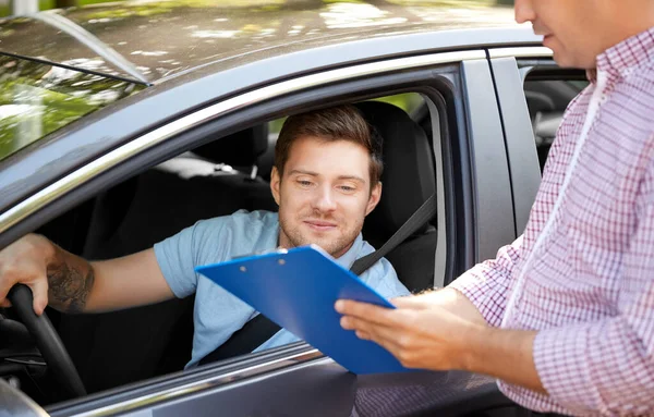 Car driving instructor with clipboard and driver — Stock Photo, Image