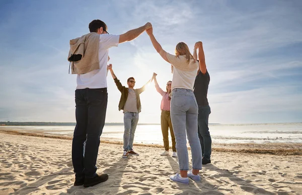 Amis heureux se tenant la main sur la plage d'été — Photo