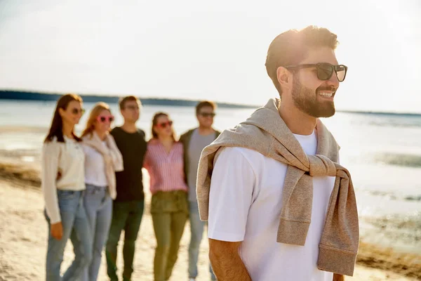 Glad man med vänner på stranden på sommaren — Stockfoto