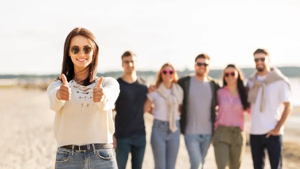 Kobieta z przyjaciółmi na plaży pokazuje kciuki w górę — Zdjęcie stockowe