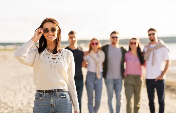 Donna felice con gli amici sulla spiaggia in estate — Foto Stock