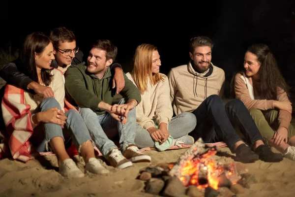 Gruppo di amici seduti al fuoco del campo sulla spiaggia — Foto Stock