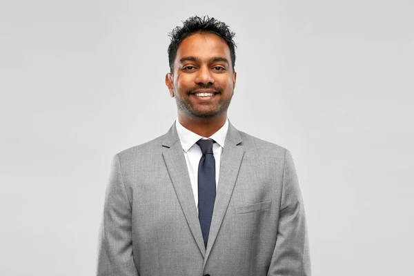 Smiling indian businessman over grey background — Stock Photo, Image