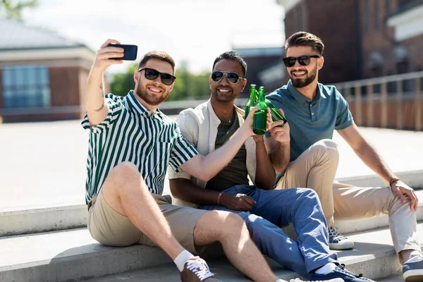 Männer stoßen Bier an und machen Selfie mit dem Smartphone lizenzfreie Stockbilder