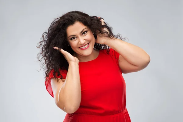 Mulher feliz tocando seu cabelo sobre fundo cinza — Fotografia de Stock