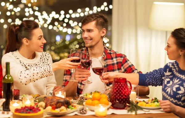 Szczęśliwy przyjaciele pijący czerwone wino na przyjęciu świątecznym — Zdjęcie stockowe