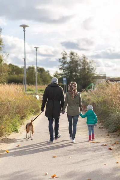 Gelukkig familie wandelen met hond in de herfst — Stockfoto