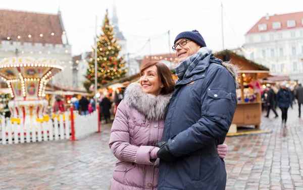 Счастливая пожилая пара обнимается на рождественском рынке — стоковое фото