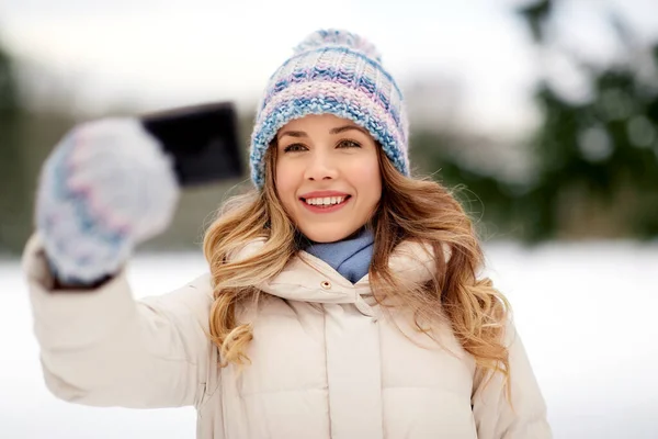 Женщина делает селфи на смартфоне зимой — стоковое фото