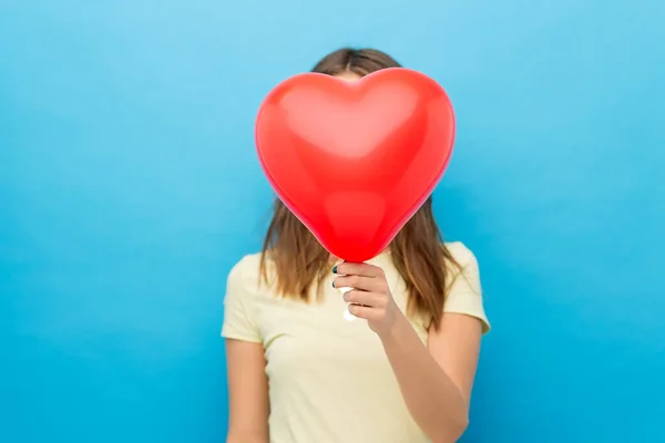 Kobieta zakrywająca twarz balonem w kształcie serca — Zdjęcie stockowe