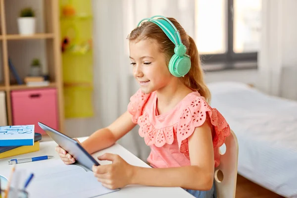 Meisje in hoofdtelefoon met tablet computer thuis — Stockfoto