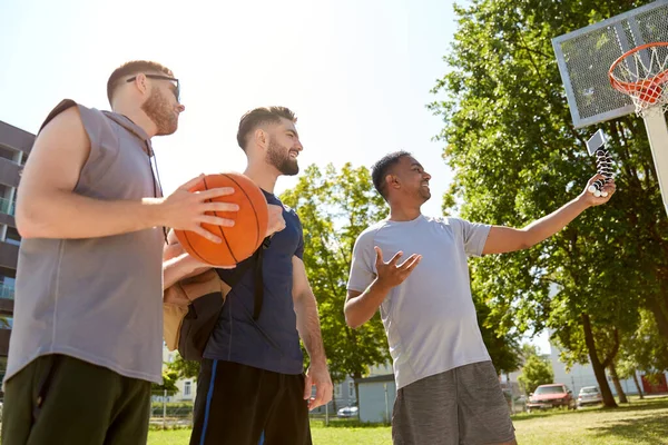 Счастливые мужчины делают селфи на баскетбольной площадке — стоковое фото