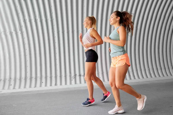 Mujeres jóvenes o amigas corriendo al aire libre — Foto de Stock