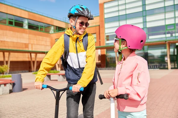 Gelukkige schoolkinderen met rugzakken en scooters — Stockfoto