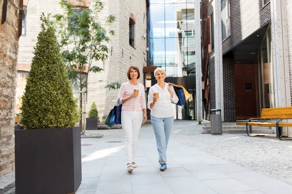 Senior vrouwen met boodschappentassen en koffie in de stad — Stockfoto