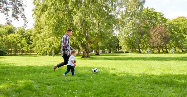 Feliz padre e hijo jugando al fútbol en el parque de verano —  Fotos de Stock