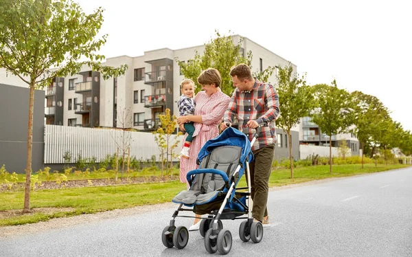 Familie met baby en wandelwagen wandelen langs de stad — Stockfoto