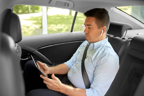 Passagerare med hörlurar och surfplatta i taxibil — Stockfoto