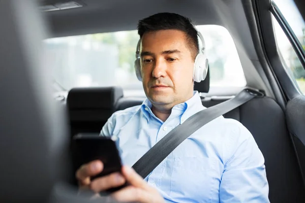 Cestující se sluchátky pomocí smartphonu v autě — Stock fotografie
