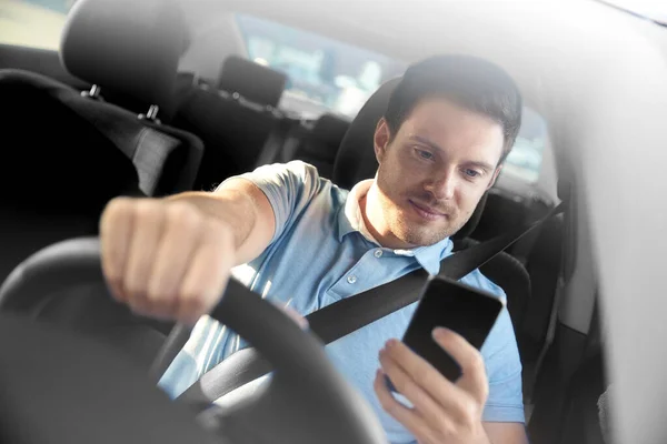 Людина керує автомобілем і використовує смартфон — стокове фото