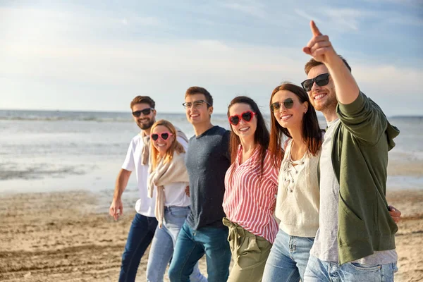 Happy friends walking along summer beach — Stock Photo, Image