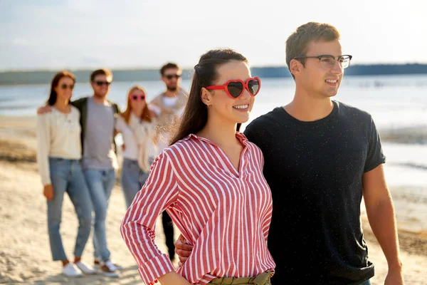 Amici felici passeggiando lungo la spiaggia estiva — Foto Stock