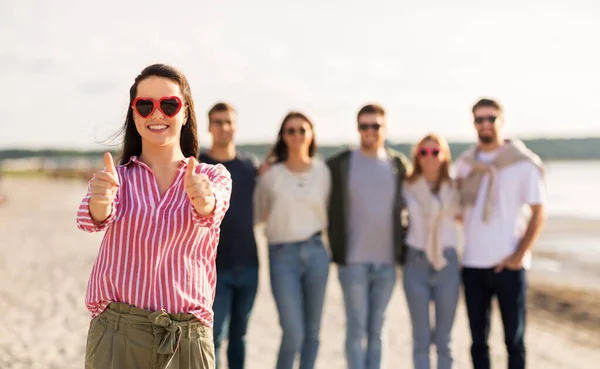 Woman with friends on beach showing thumbs up — Stock Photo, Image