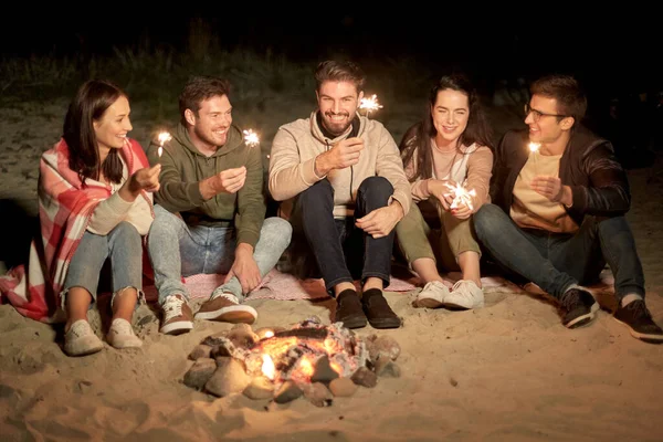 Amis heureux avec des étincelles au feu de camp la nuit — Photo