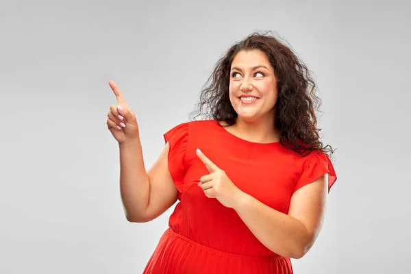 Šťastná žena v červených ukazujících prsty na něco — Stock fotografie