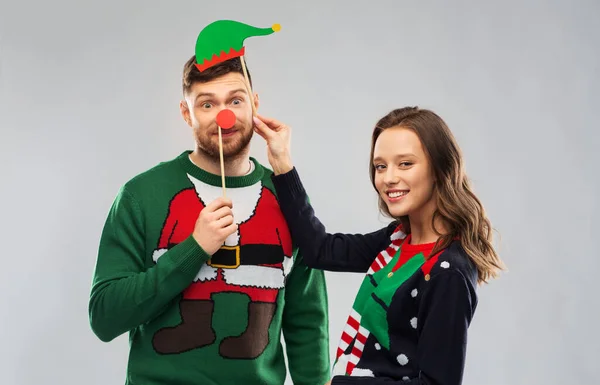 Par med julfest rekvisita i fula tröjor — Stockfoto