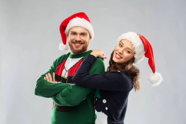 Šťastný pár v vánoční svetry a Santa klobouky — Stock fotografie