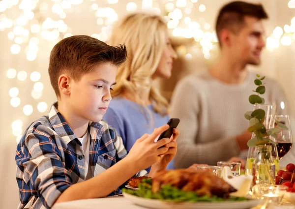 Мальчик со смартфоном на семейном ужине — стоковое фото